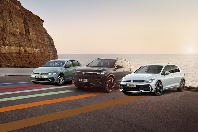 Drei Volkswagen-Pkw nebeneinander auf einer Straße vor einer Felswand bei Sonnenuntergang