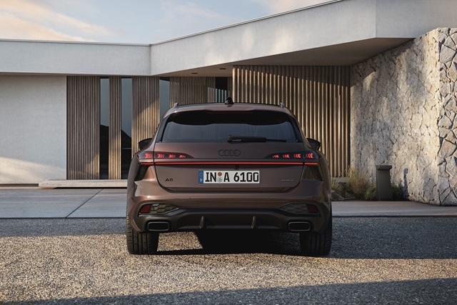 Der Audi A6 Avant parkend vor einem modernen Gebäude in Heckansicht.