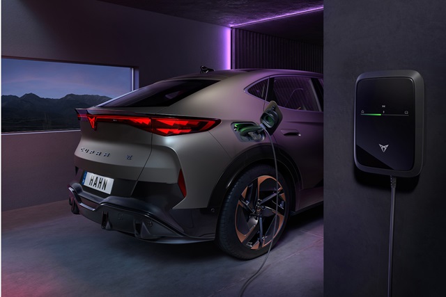 Der hintere Teil des CUPRA Tavascan Black Edition beim Laden, in einem modernen Gebäude mit lila Neonlicht