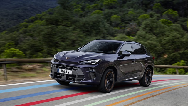 Cupra Terramar E-Hybrid SUV in lila Frontansicht auf einer Straße mit farbigen Linien und bewaldetem Hintergrund