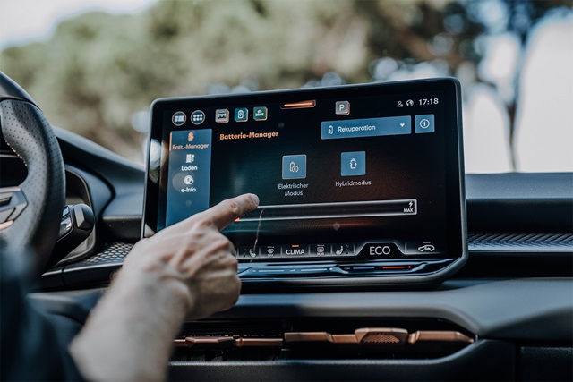 Nahaufnahme des Infotainment-Displays im CUPRA Terramar mit Finger, der auf den Bildschirm zeigt, auf dem der Batterie-Manager und verschiedene Modi angezeigt werden.