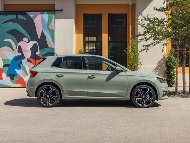 Hellgrüner Škoda Fabia in Seitenansicht vor einem Gebäude mit bunter Wandmalerei und Fenstern