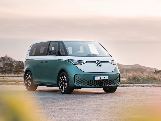 VW ID. Buzz in grün-weiß mit markantem Frontdesign und LED-Scheinwerfern auf einer Straße vor Dünenlandschaft