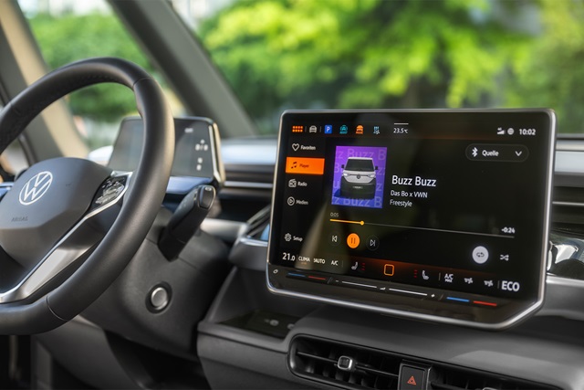 Cockpit des VW ID. Buzz mit Lenkrad und großem Infotainment-Display, das die Musikwiedergabe von 'Buzz Buzz' zeigt.