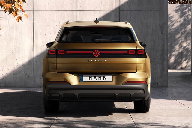 Heckansicht eines bronzefarbenen VW ID. Tiguan mit markantem schwarzen Leuchtband und quadratischen Rückleuchten vor einer Betonwand