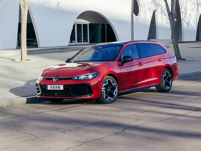 Roter VW Passat R-Line in der Seitenansicht vor einem modernen Gebäude und auf einer Straße