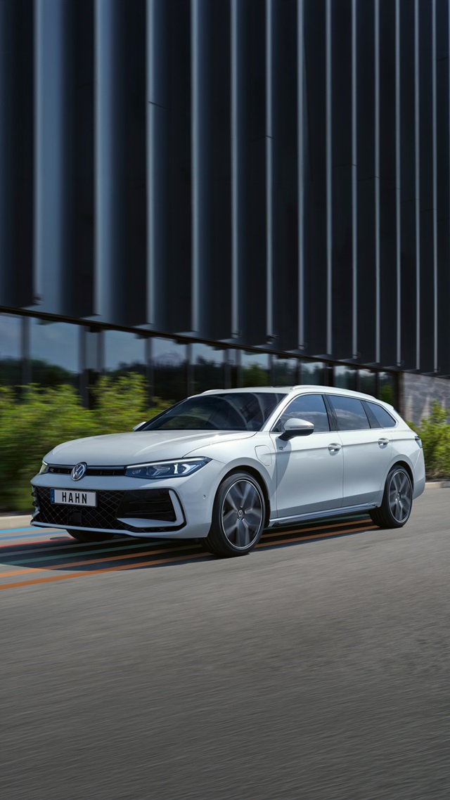Weißer VW Passat R-Line Kombi in Seitenansicht mit markanten Felgen und sichtbarem Kühlergrill vor einem modernen Gebäude