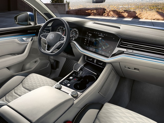 Innenraum eines VW Touareg mit Lenkrad, digitalem Armaturenbrett, Mittelkonsole mit Touchscreen und hellen, gesteppte Sitzen