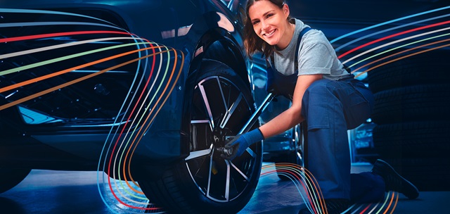 Eine Mechanikerin wechselt Räder.